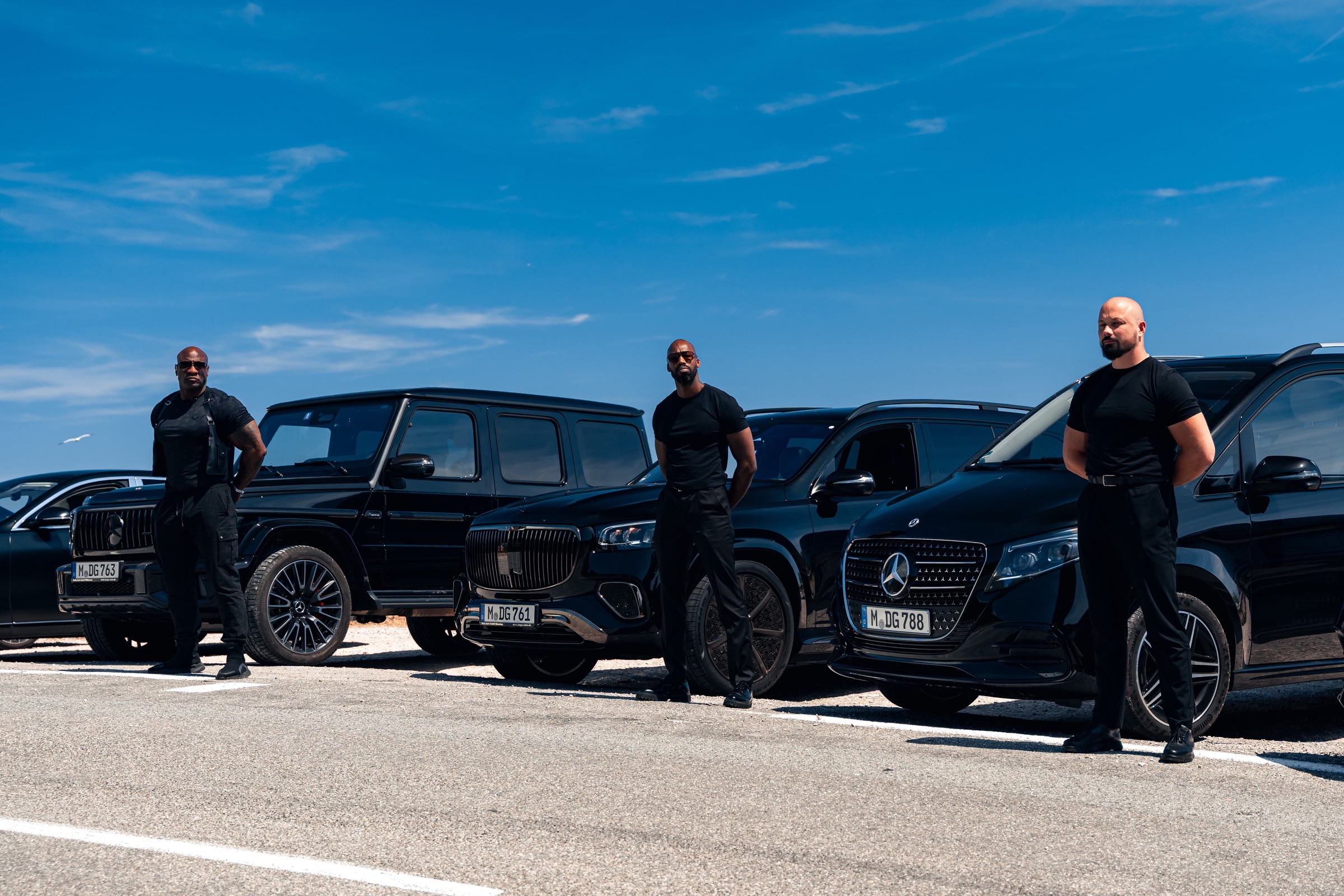 LEON security drivers standing beside black Mercedes vehicles